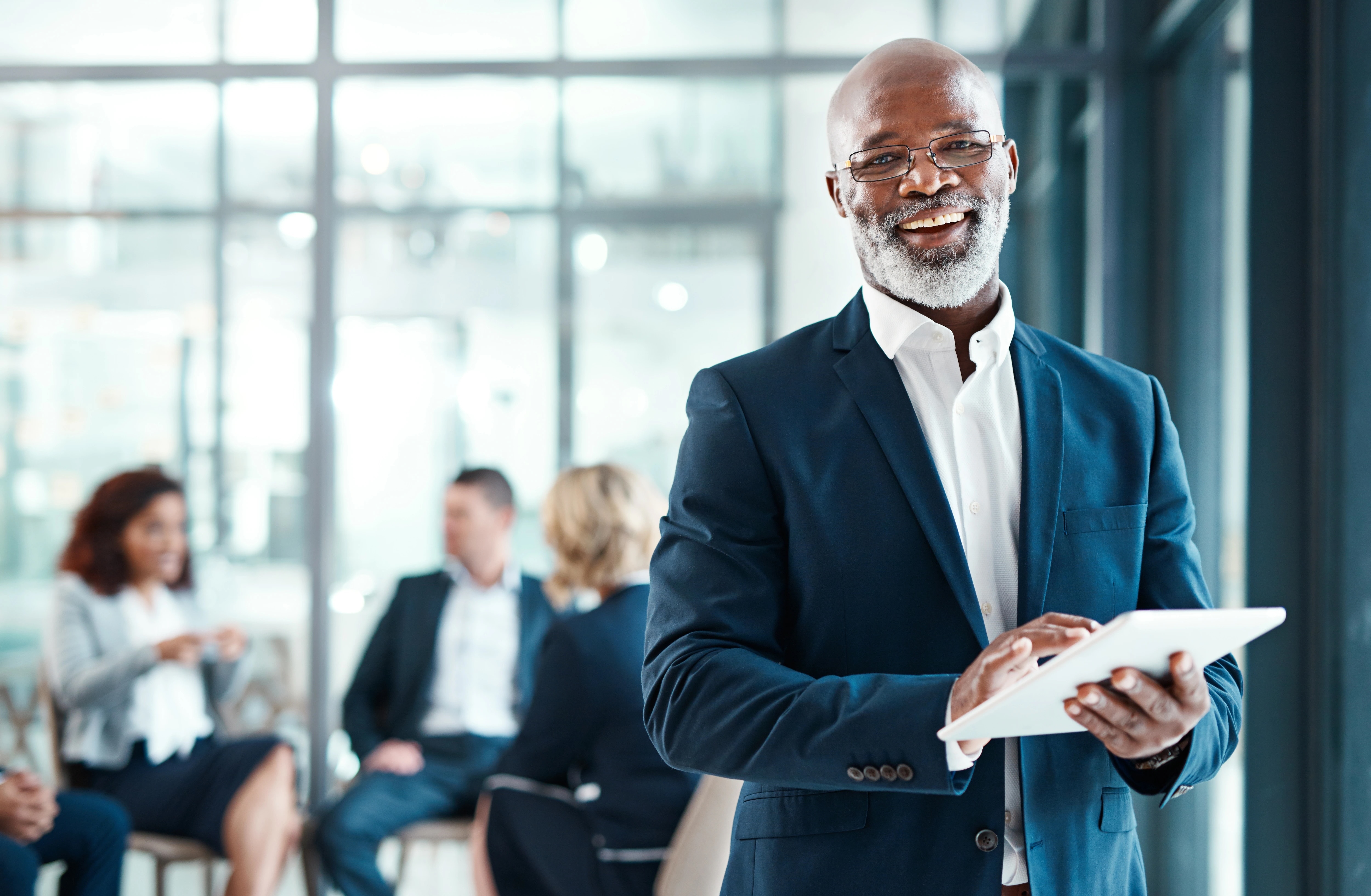 Man smiling and holding tablet in an office