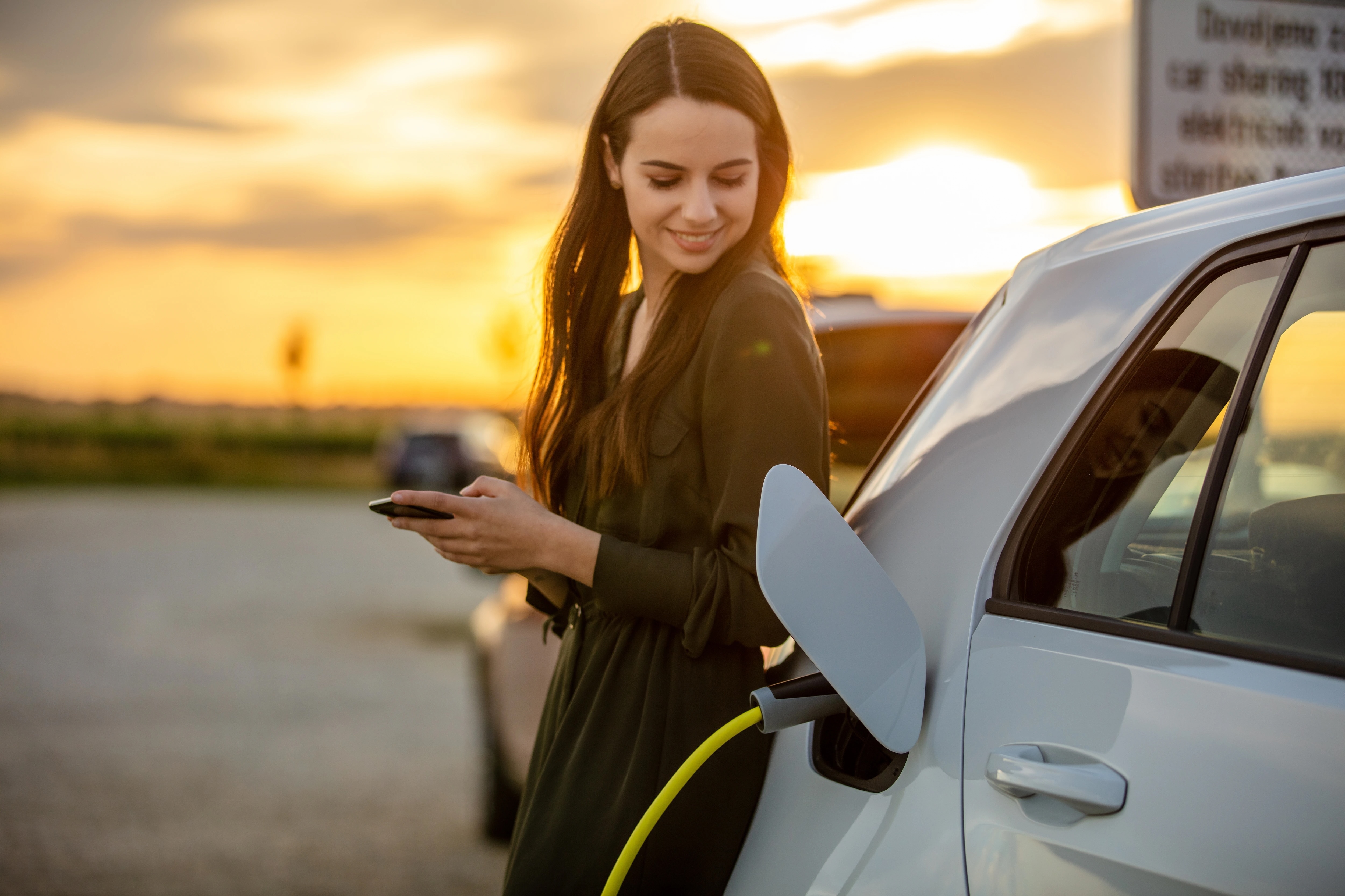 Woman leaning against car while pumping gas