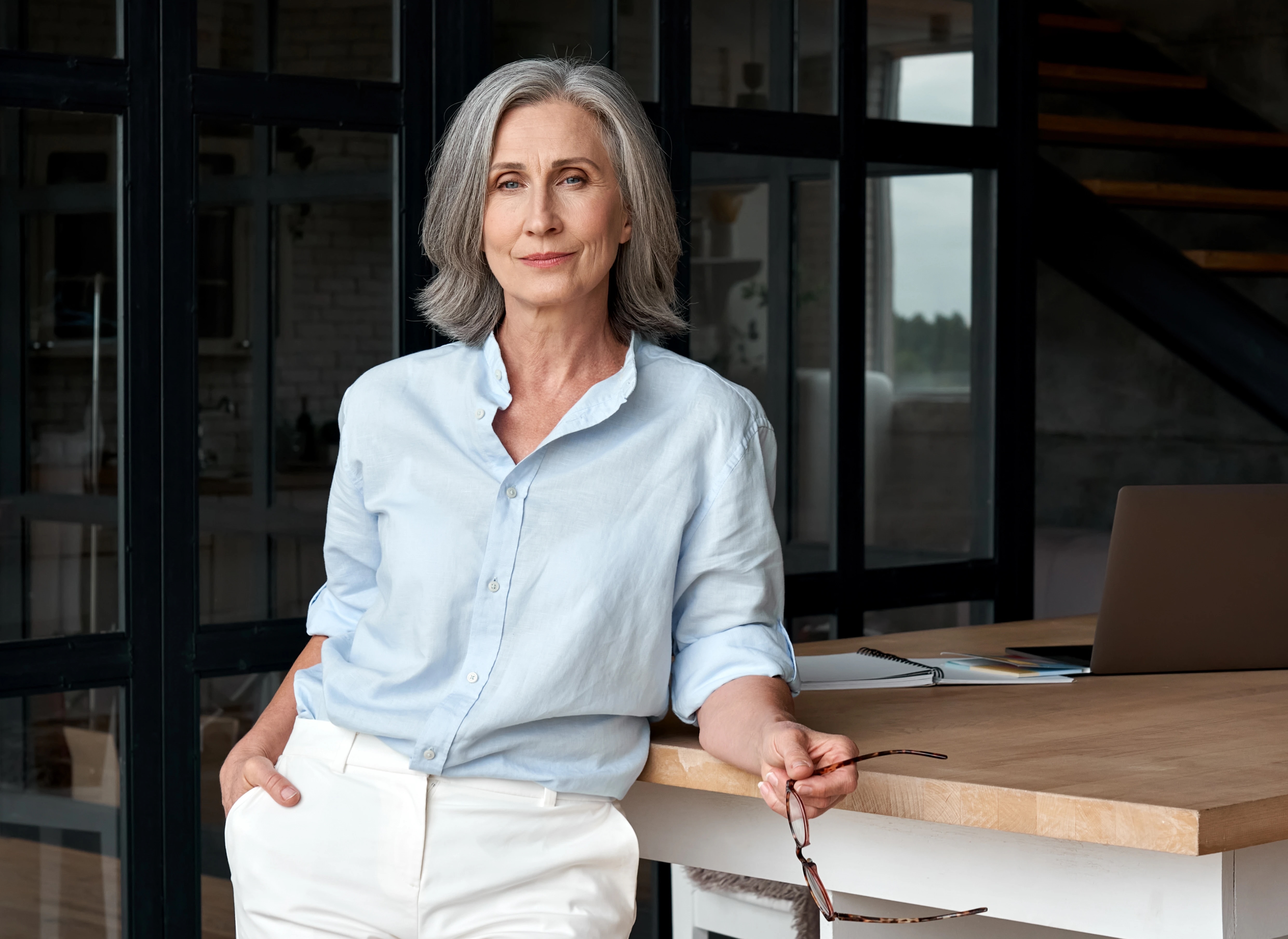 Grey-haired woman leaning against table