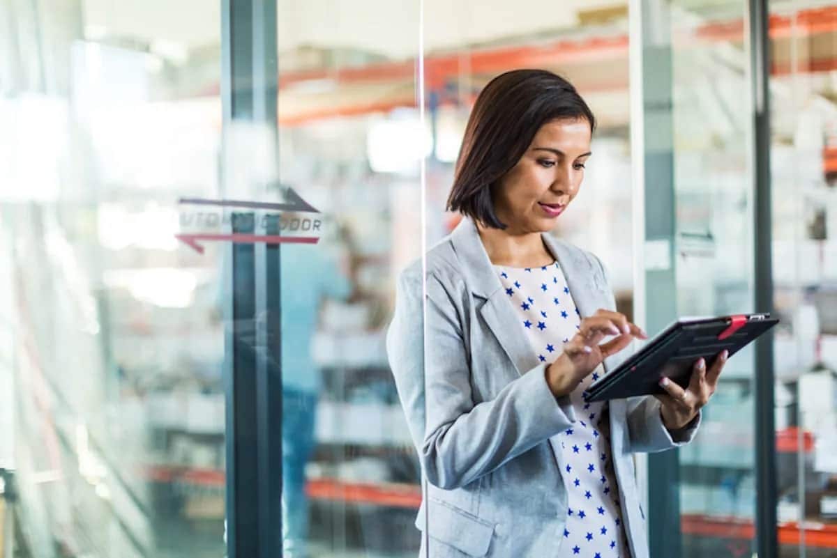 Woman standing in front of glass doors uses tablet