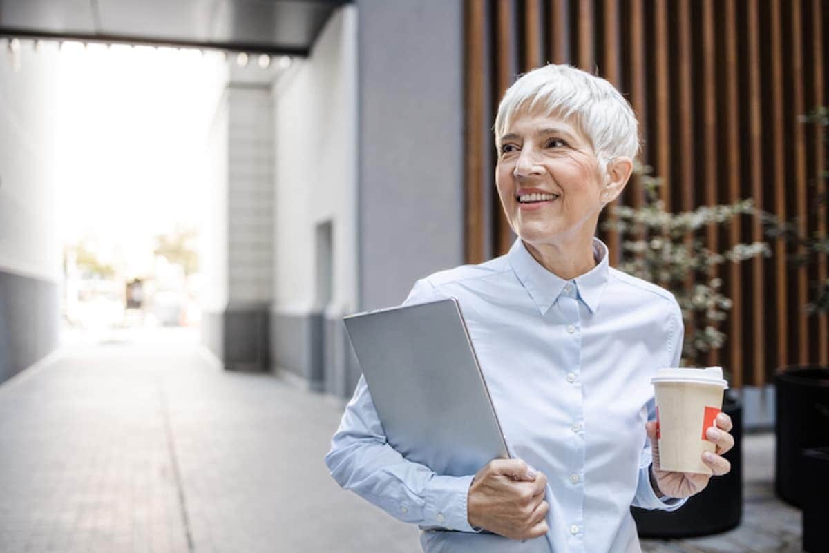 Short-haired woman carrying laptop and coffee cup