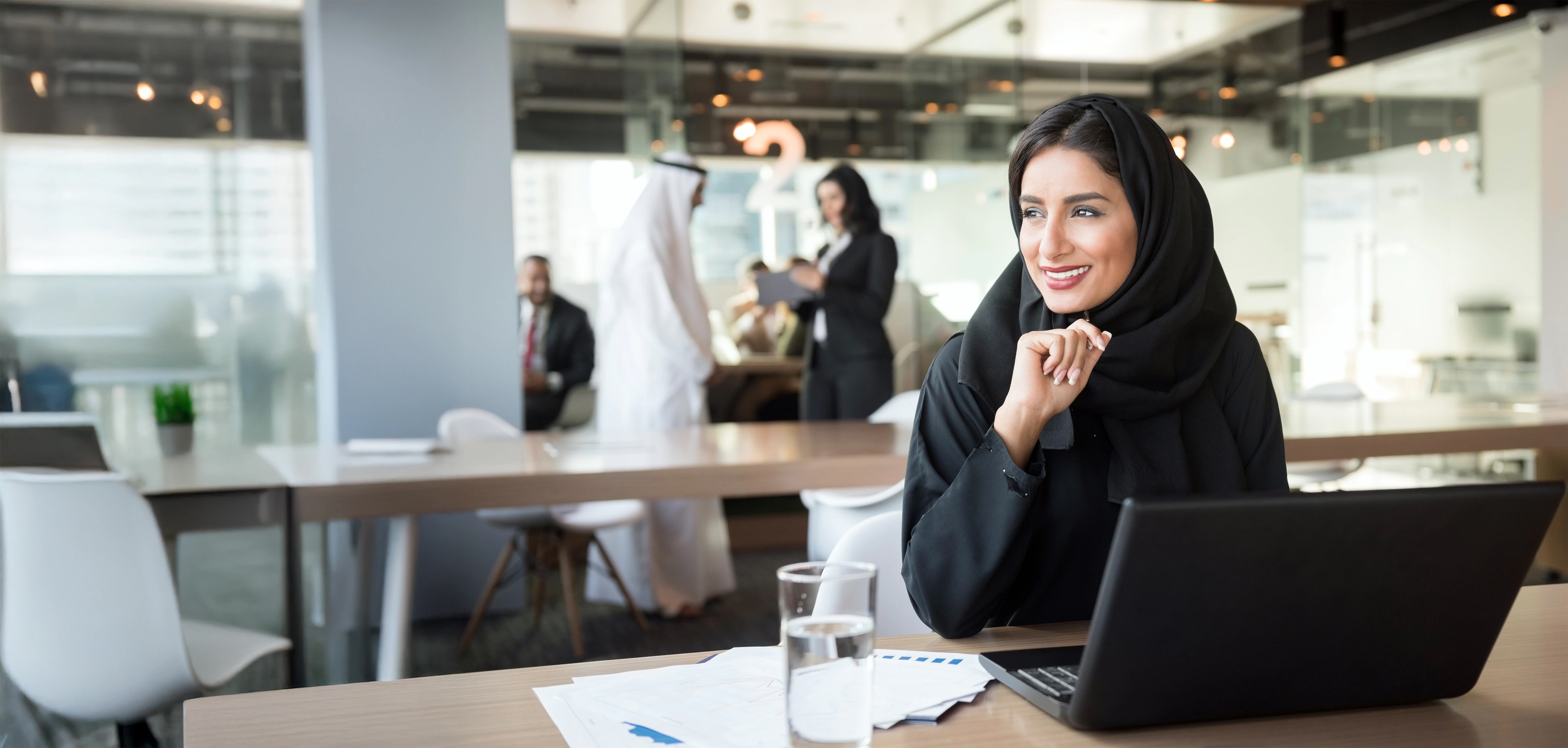 Woman wearing hijab working on laptop in an office
