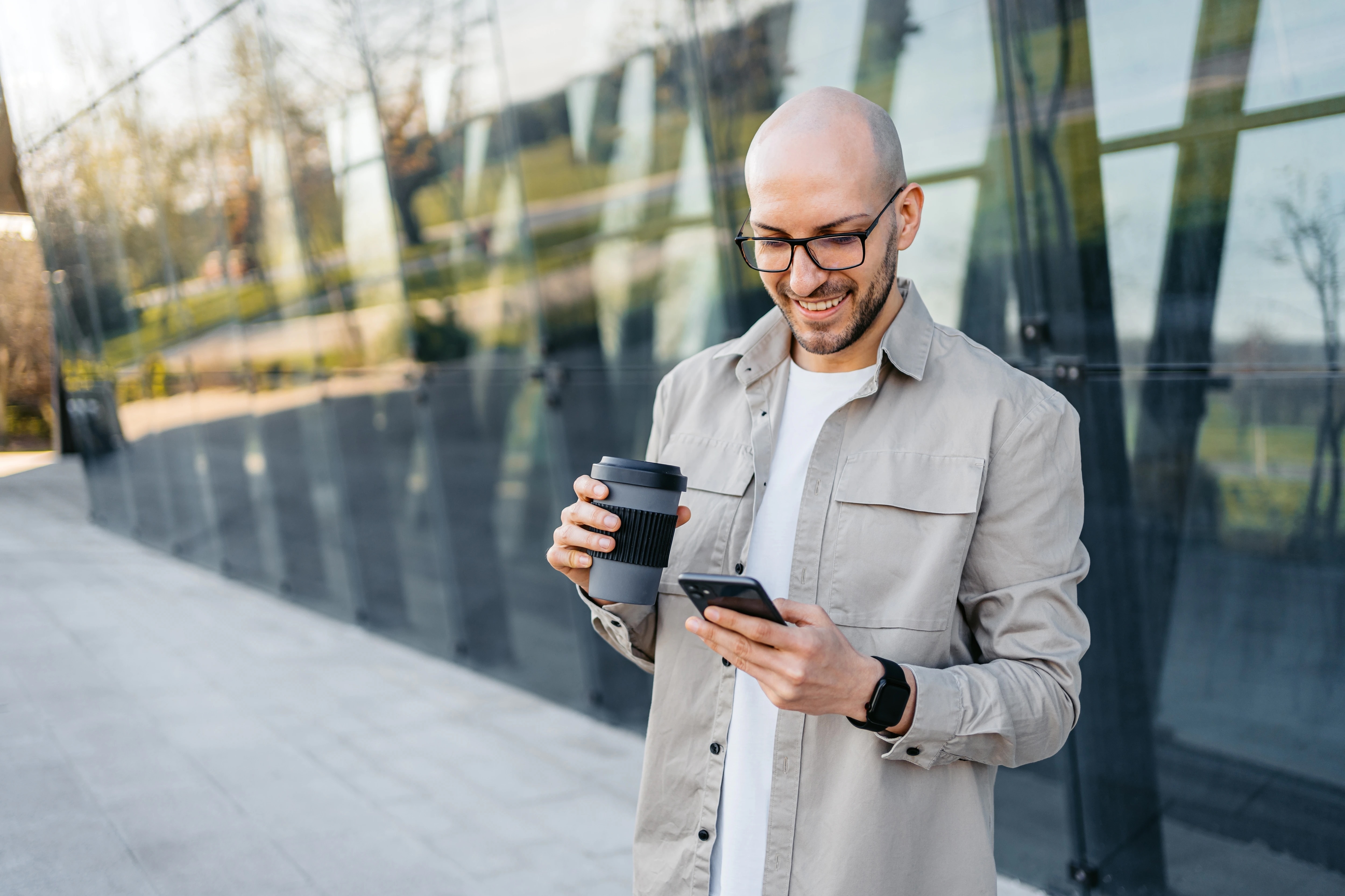 Man in cityscape holding phone and coffee
