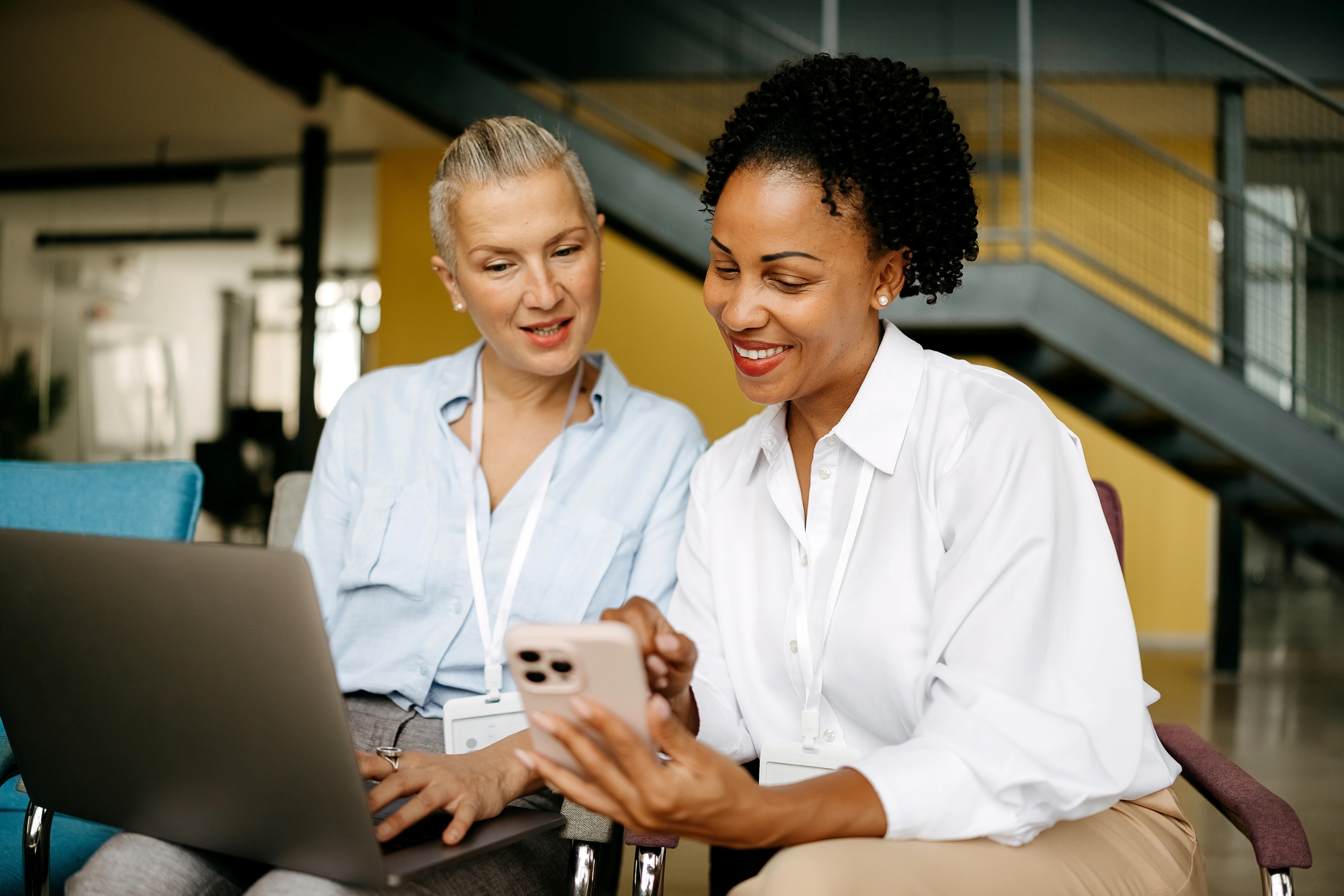 Two women looking at a laptop and cellphone