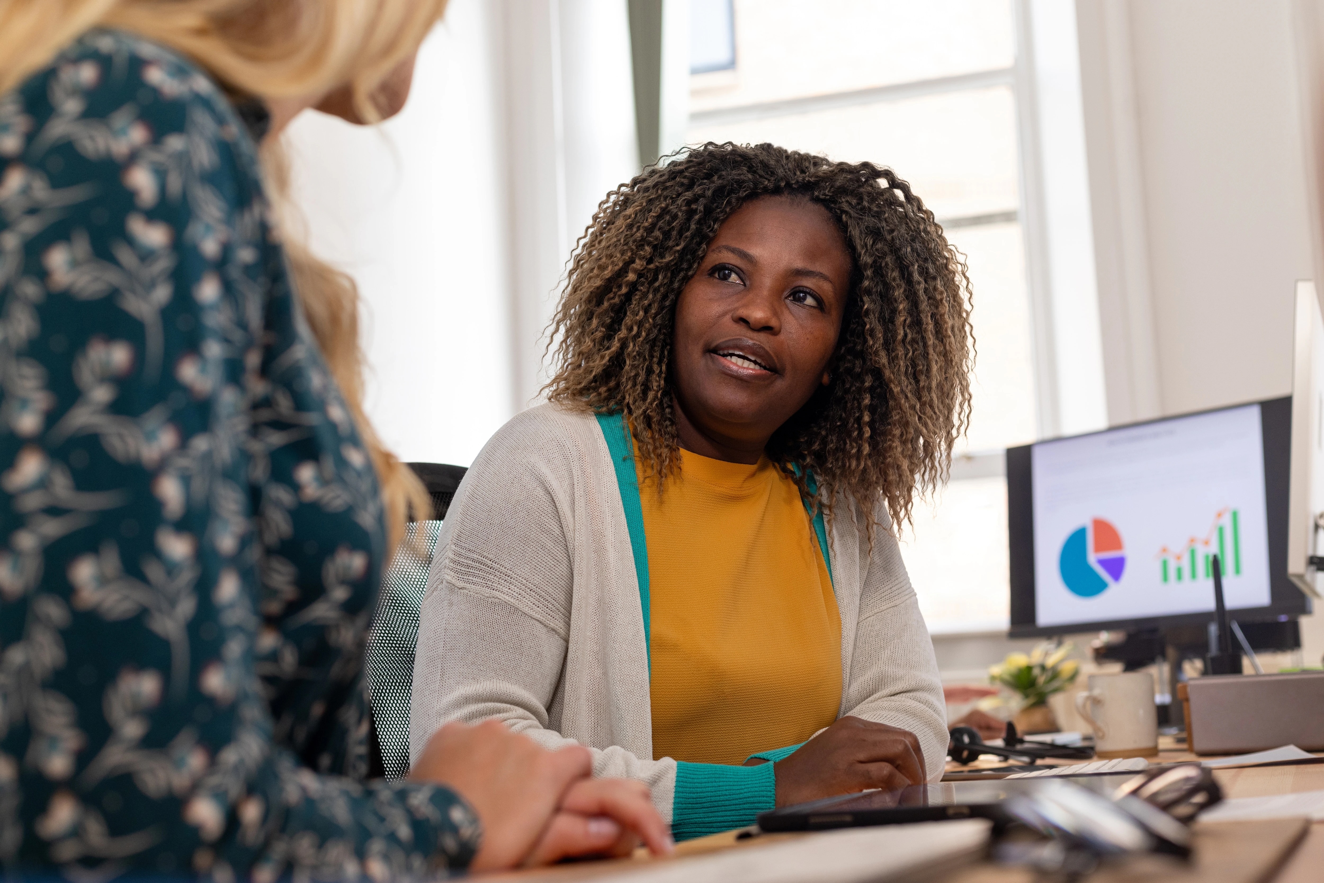 Woman talking to female coworker in office setting