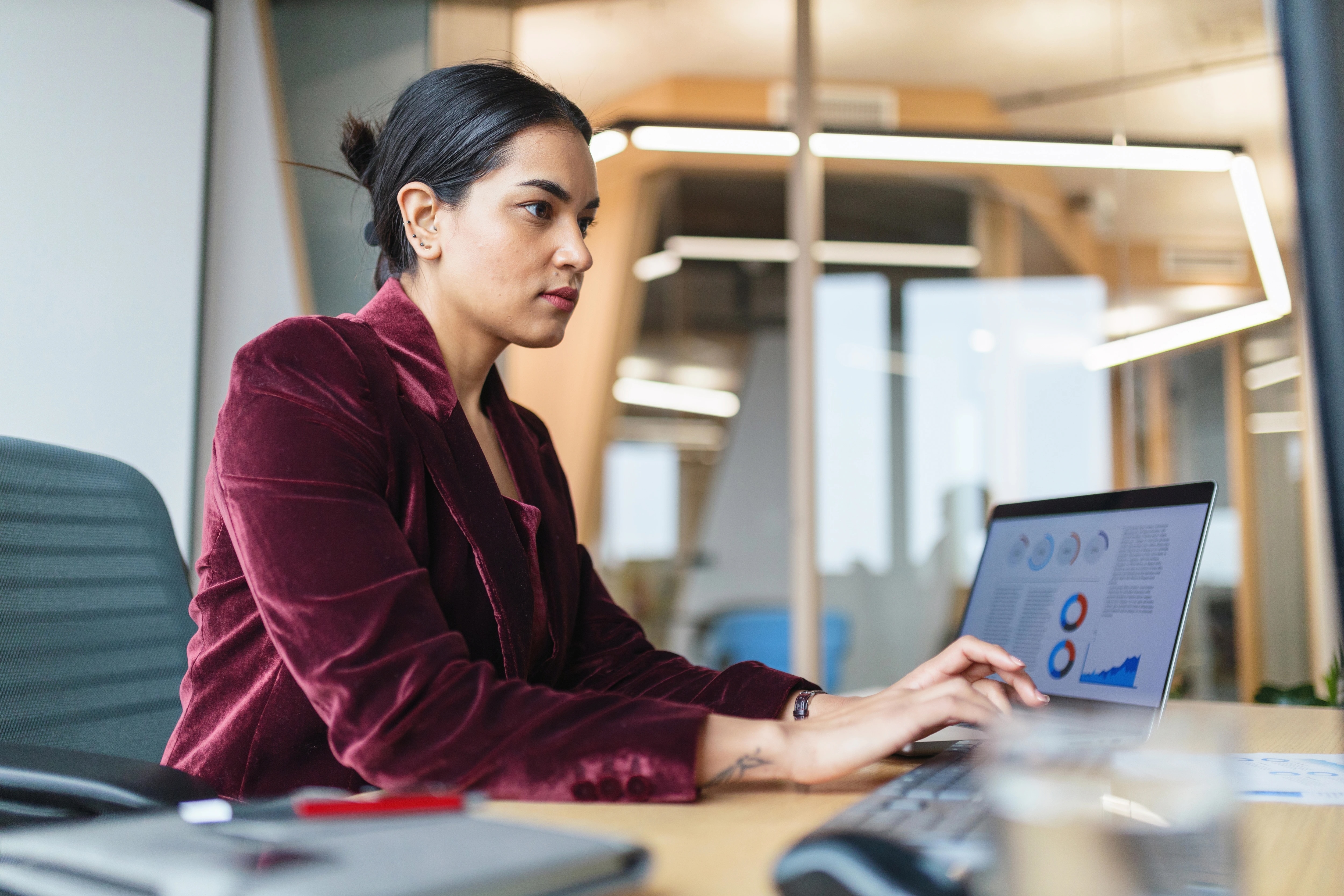 Woman working on laptop with graphs on screen