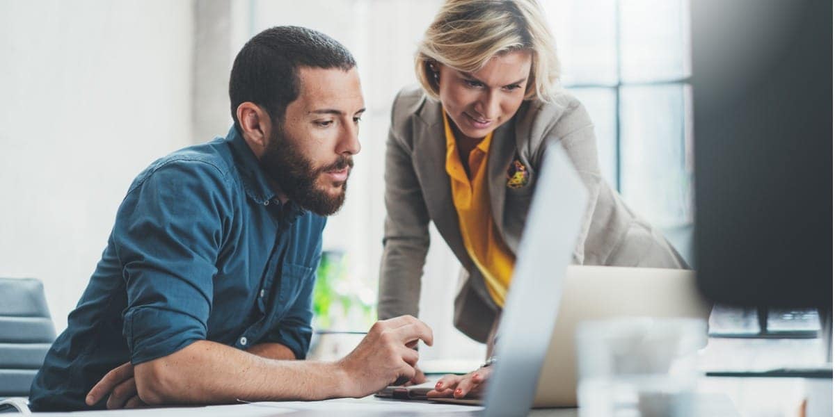 two coworkers working together on a laptop