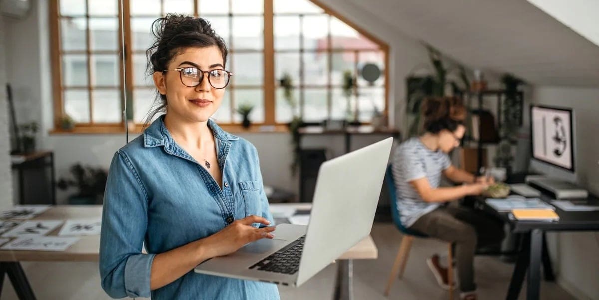 Woman with glasses holds laptop