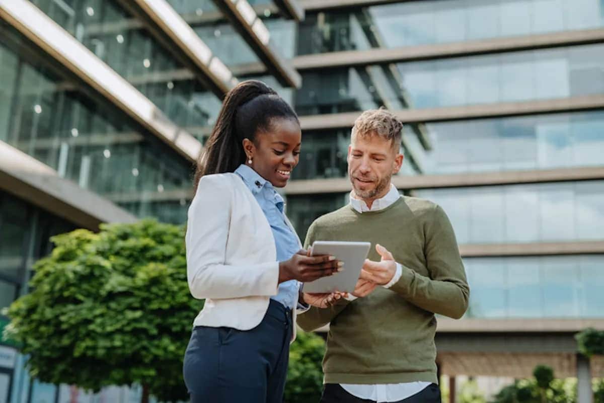 Two people standing in cityscape looking at tablet