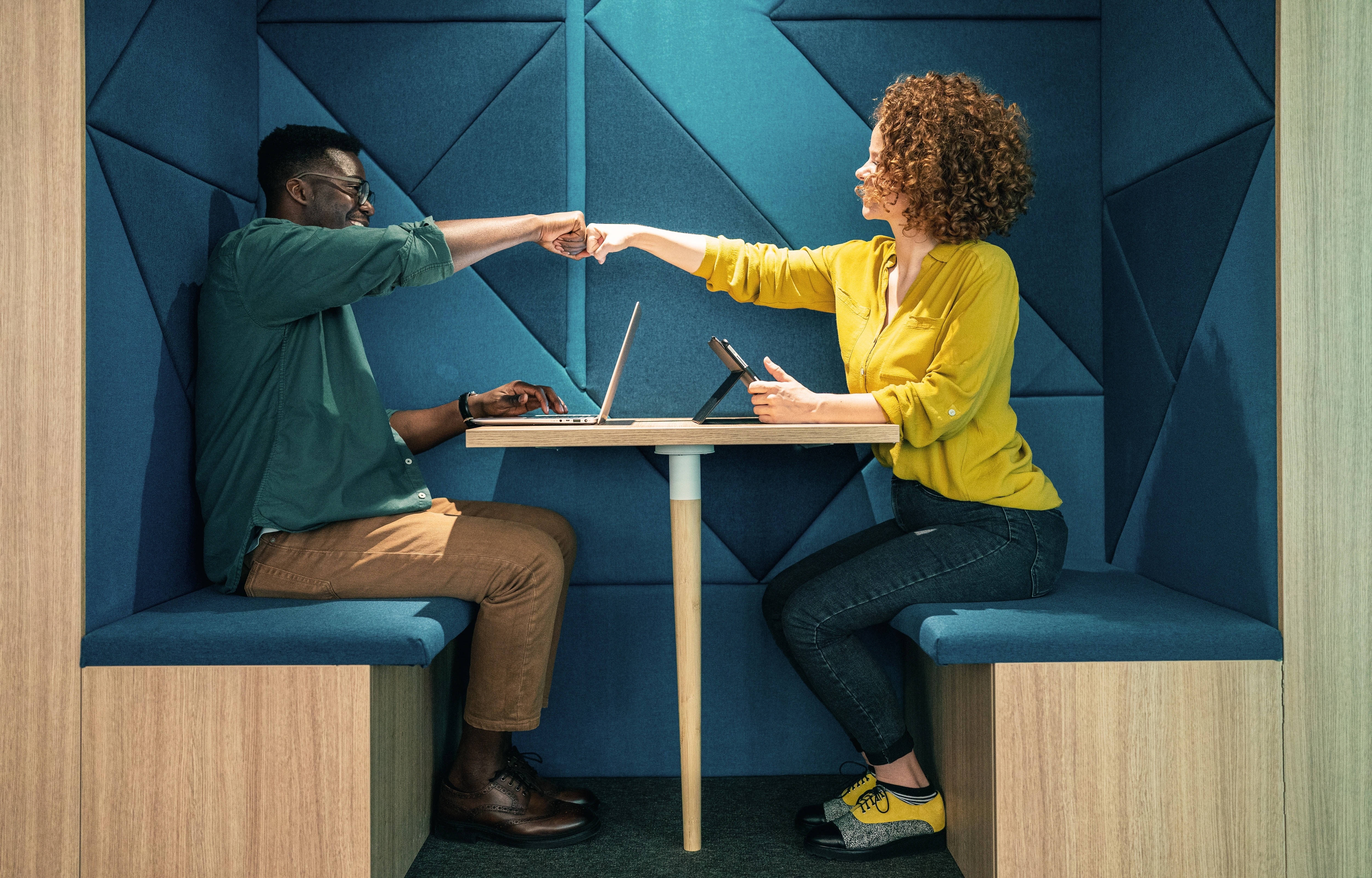 Man and woman shaking hands across the table in a booth