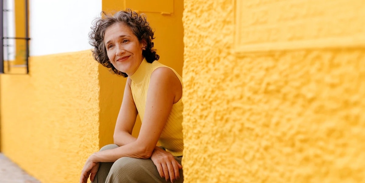 Woman in yellow sitting down against yellow wall