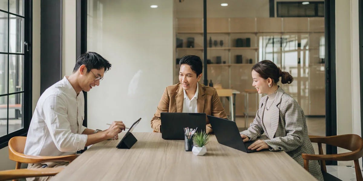 Three people sitting at a table with their laptops