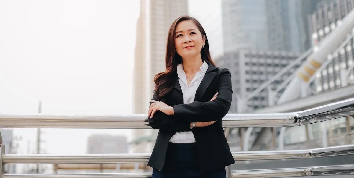 Woman crosses arms in front of cityscape