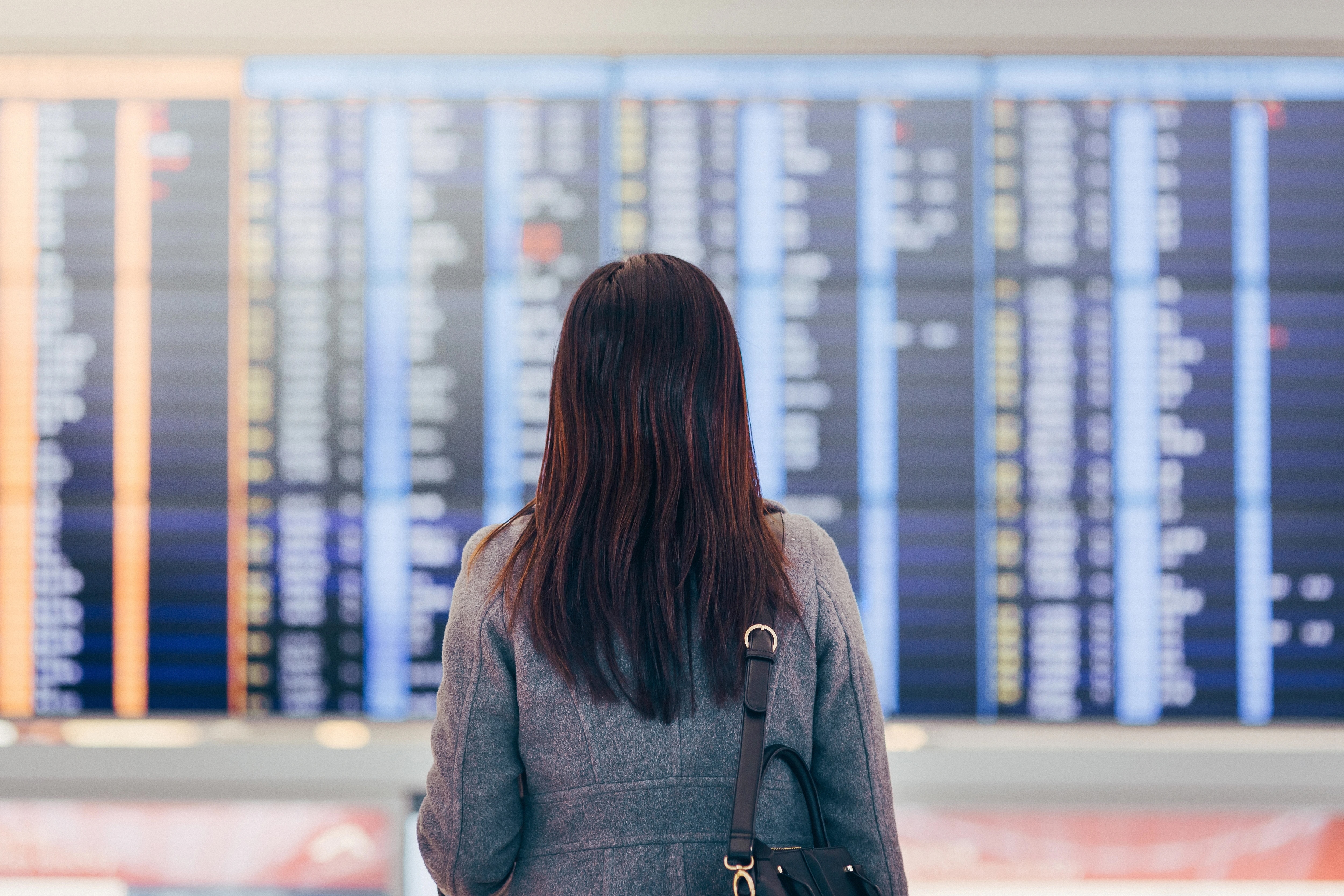 Woman in front of airport flight information board