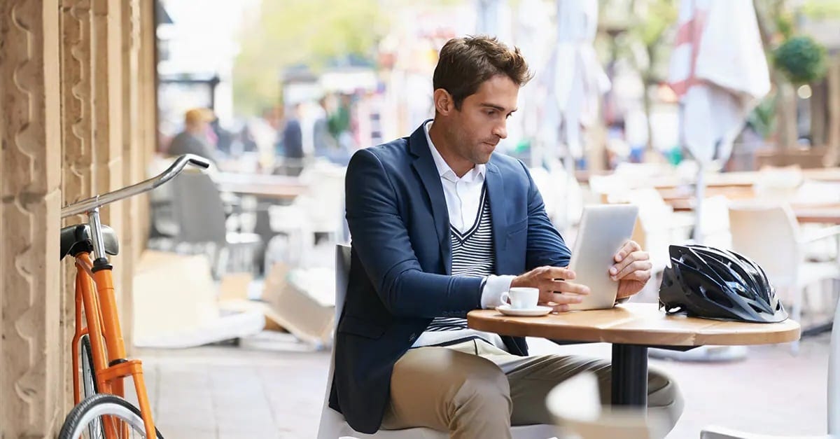 Man sitting at outdoor cafe table with tablet