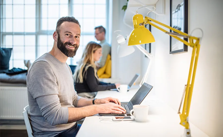 team working at desk with man looking at camera