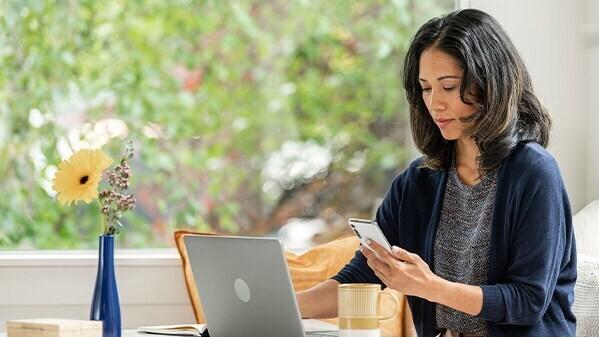 woman using phone and laptop