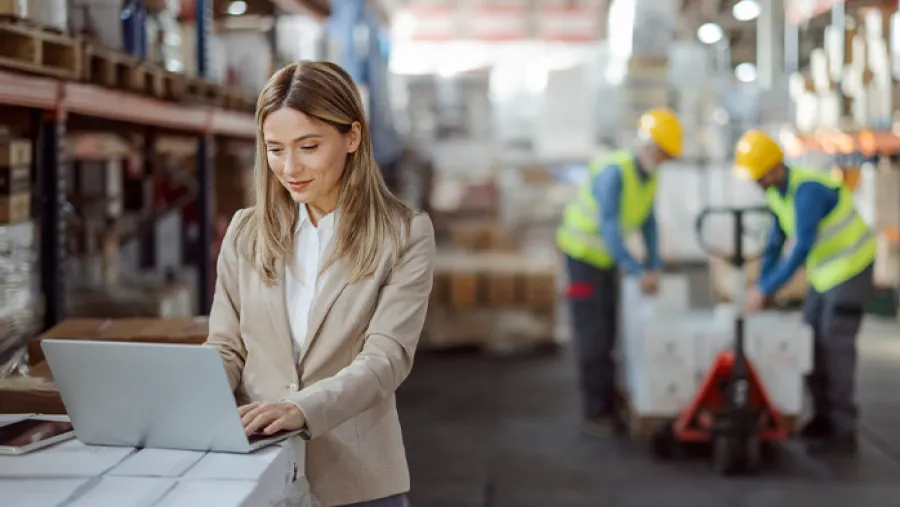 business professional working on laptop in warehouse