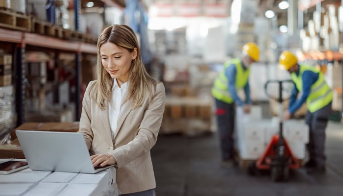 business professional working on laptop in warehouse