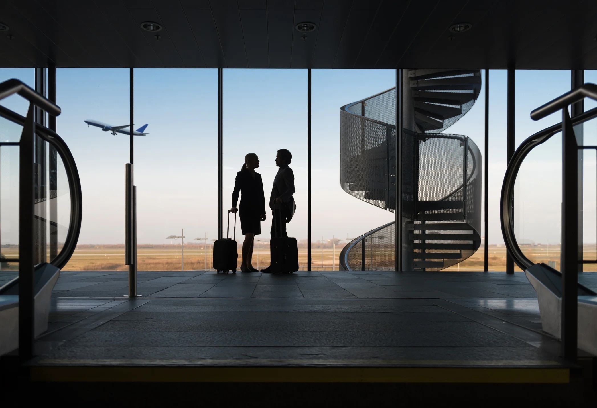 Silhouettes of two people standing in an airport