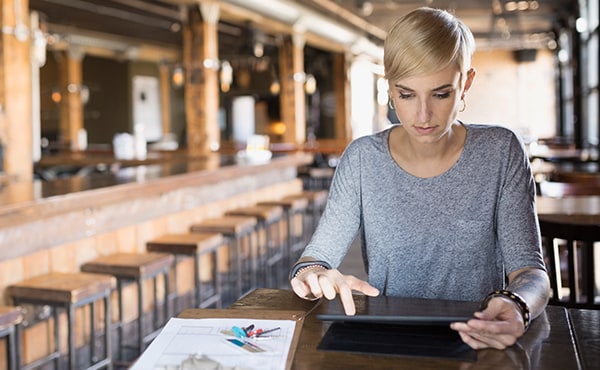 woman working on tablet in empty restaurant