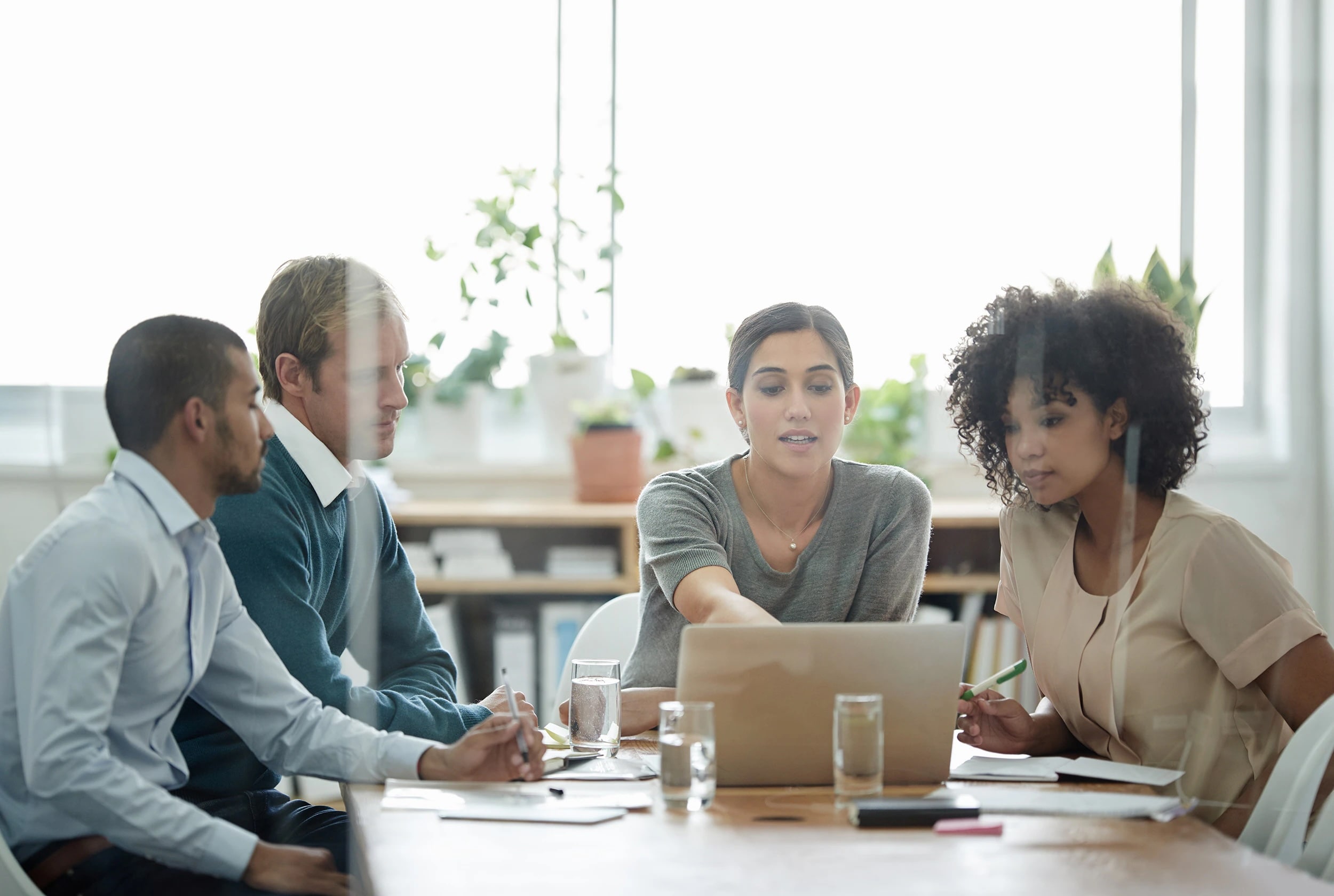 Four people sitting around a laptop