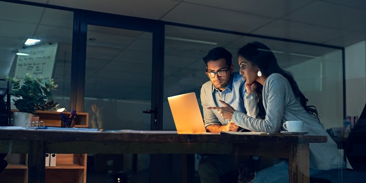 Two coworkers seated behind a laptop discussing business transformation