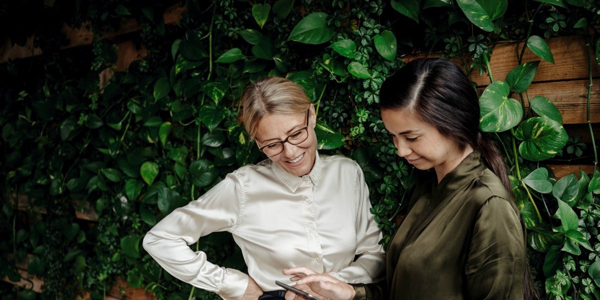 two women by green plant wall