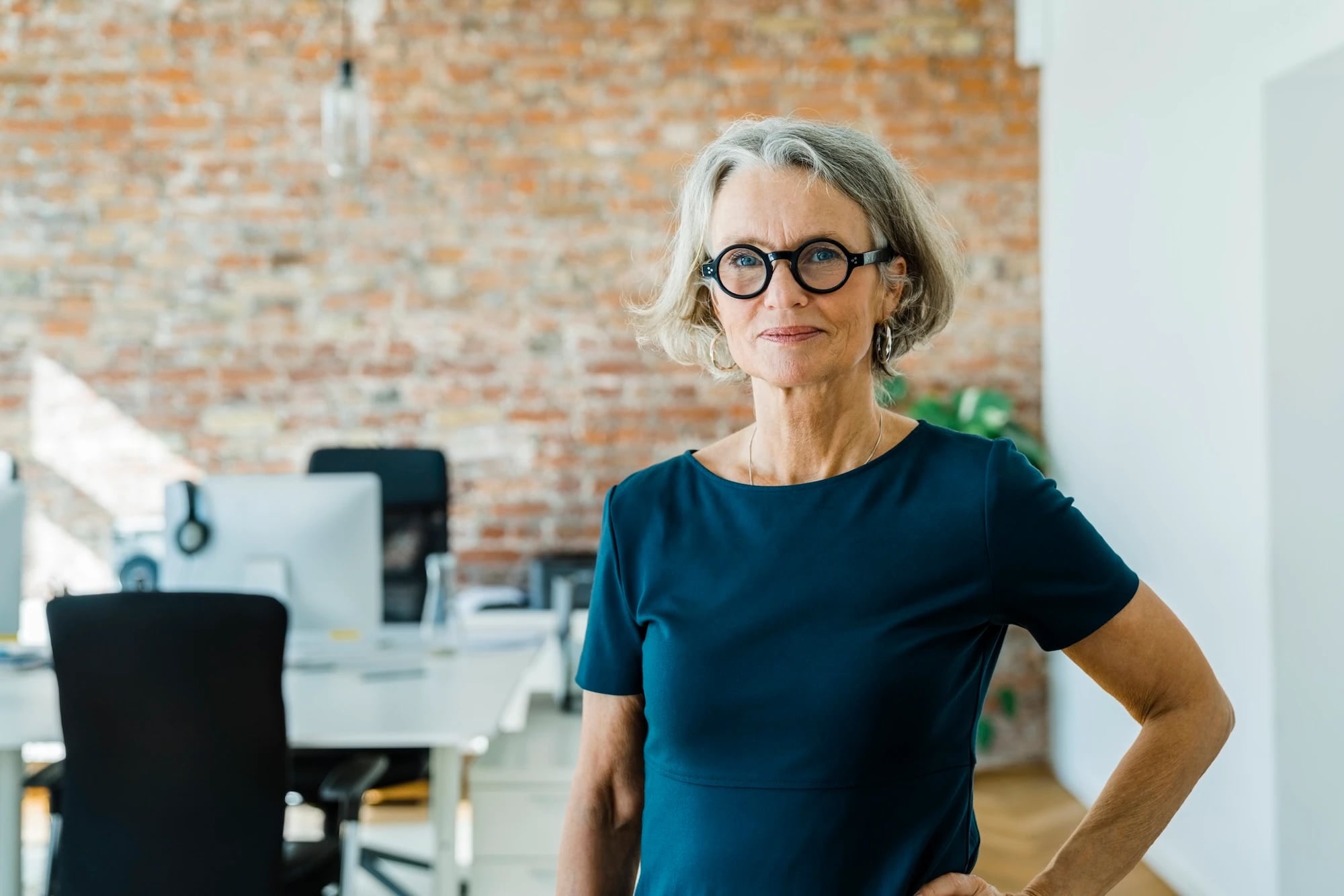 Grey-haired woman with glasses standing in office