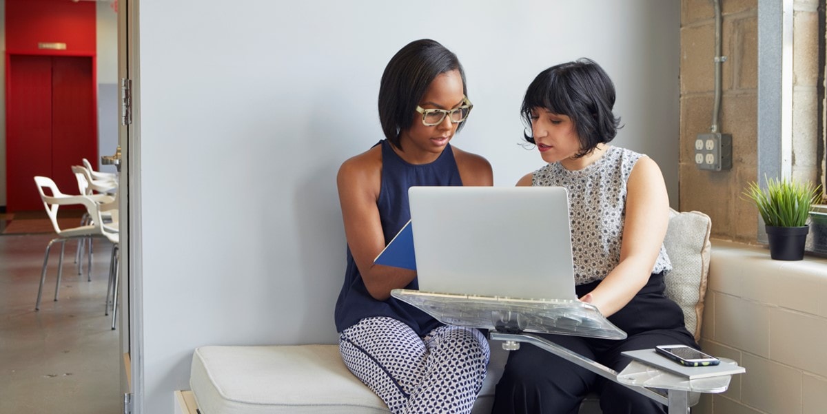 two people in office viewing laptop